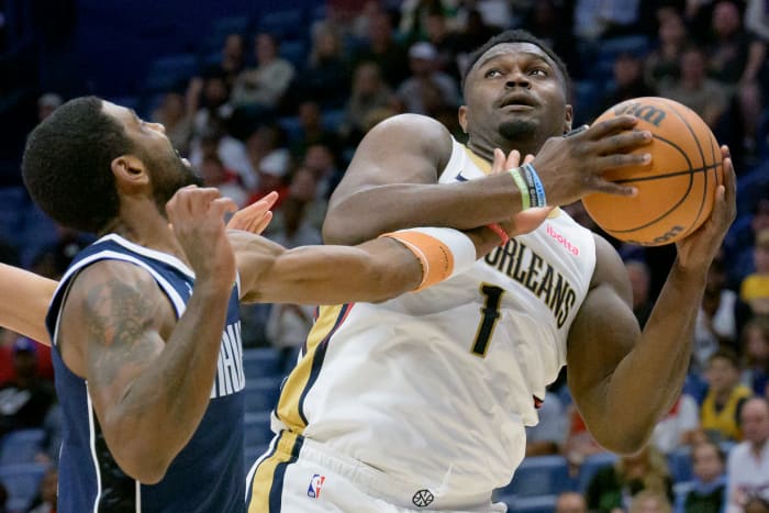 Dallas Mavs' Kyrie Irving attempts to steal the ball from New Orleans Pelcians' Zion Williamson.
